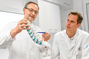 Drs. Krohmer und Rothfischer mit Wirbelsäulenmodell